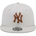 gorra-plana-beige-snapback-con-logo-marron-9fifty-league-essential-de-new-york-yankees-mlb-de-new-era